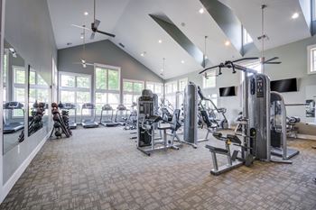 A spacious gym with a variety of equipment and a high ceiling.
